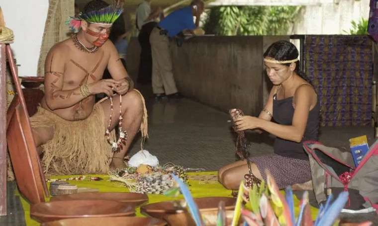 Indígenas produzindo artesanato em sua comunidade.