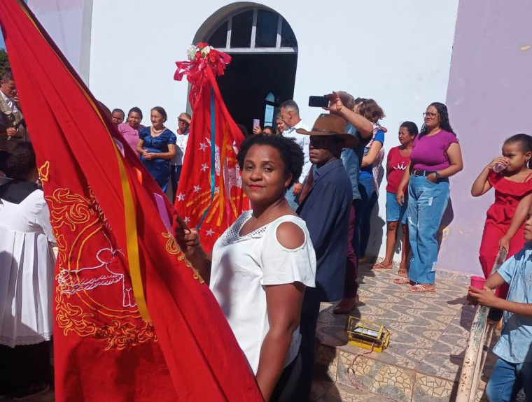 Mita empunhando a bandeira do divino em frente à igreja no município de Almas