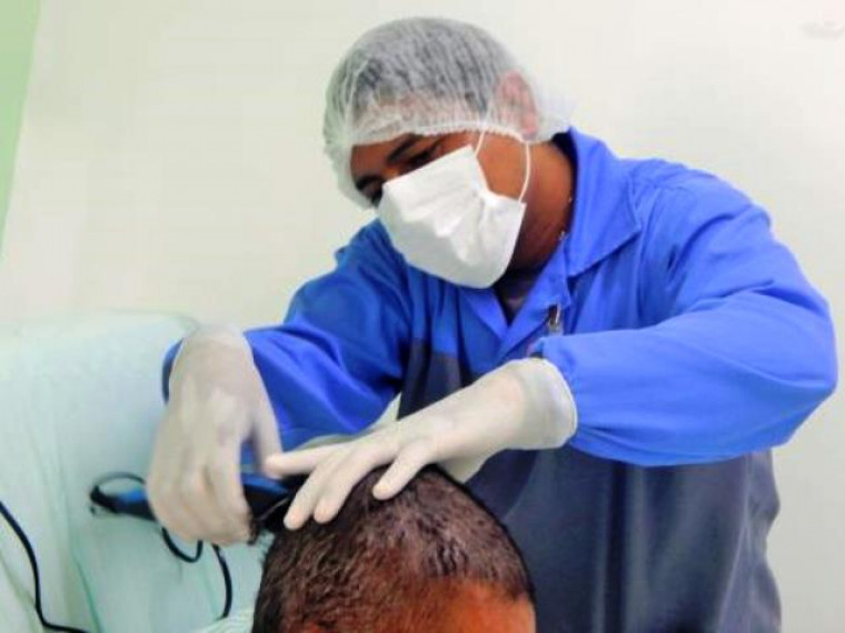 Maqueiro cortando cabelo de paciente